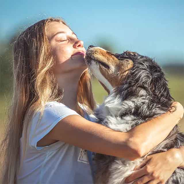 Woman petting a dog after giving him a bath with Kawell pet shampoo.